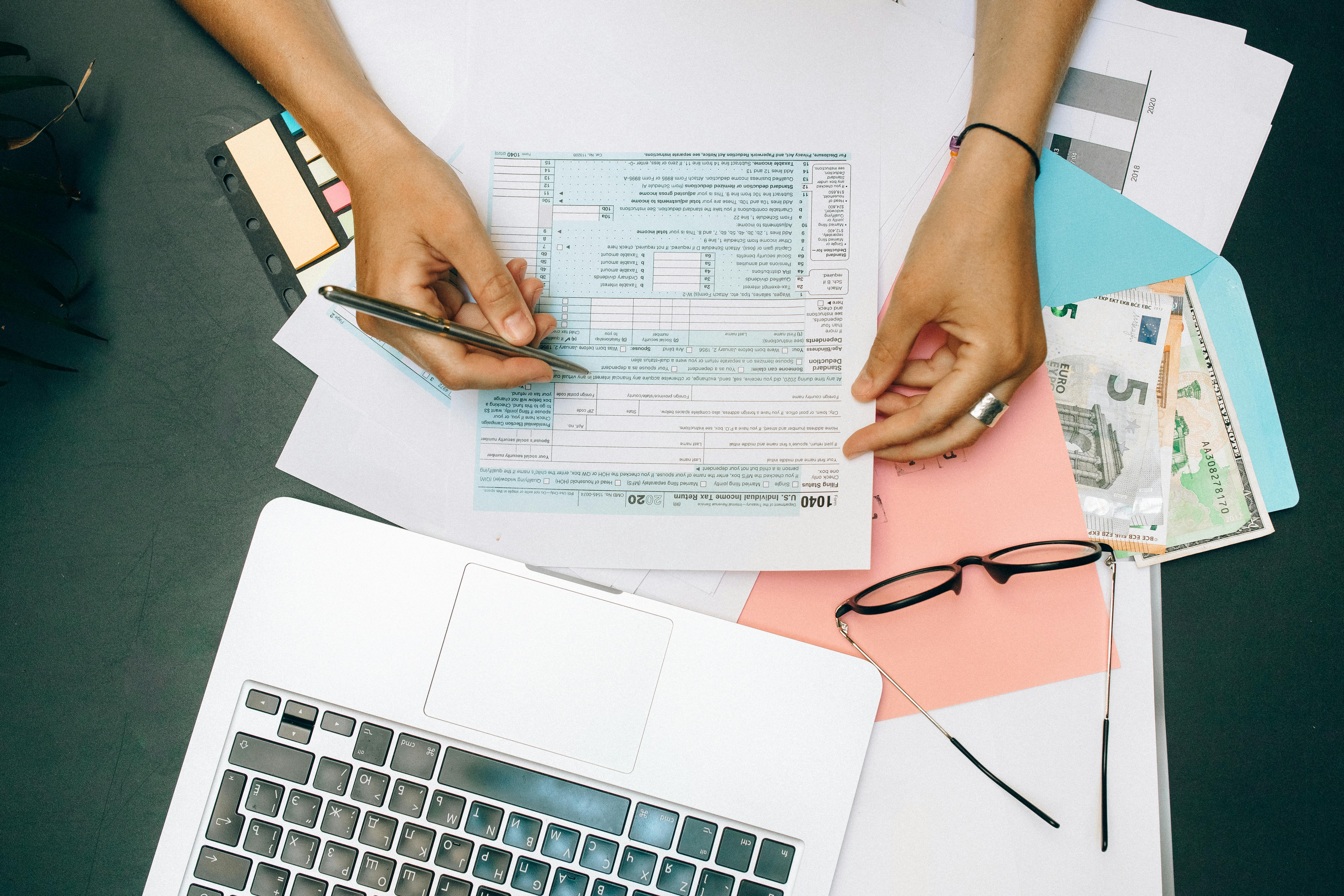 Person working on tax documents with laptop